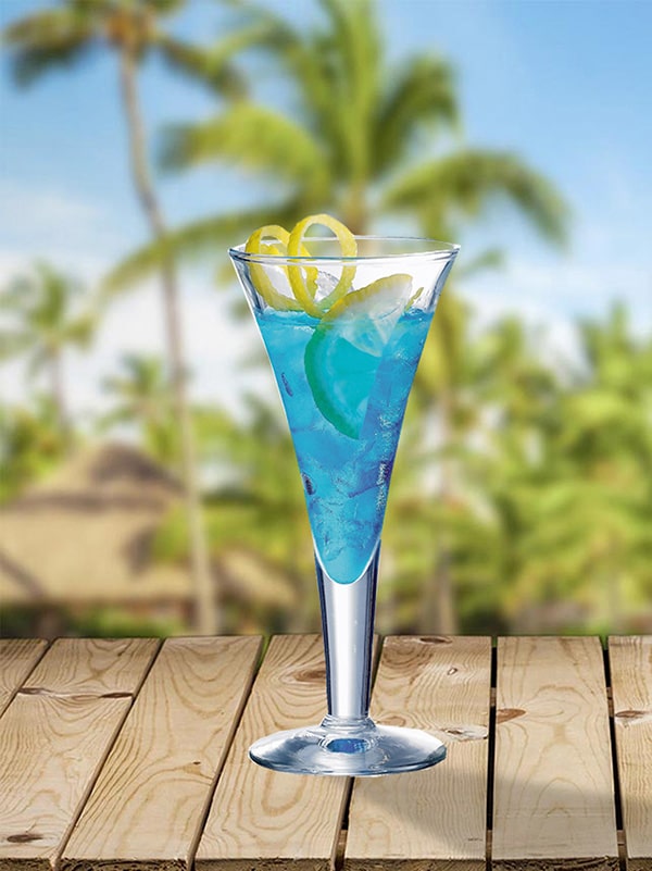 cocktail mer des antilles verre à pied avec du citron au bord de plage avec des palmiers