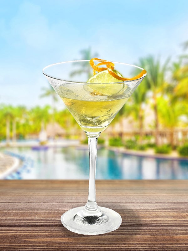 cocktail petillant au muscat avec zeste d'orange et de citron au bord d'une piscine