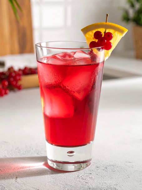 Cocktail avec vodka, crème de cassis, jus de cranberry et citron vert servi dans un verre décoré avec des groseilles