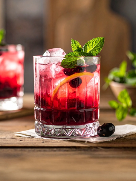 Cocktail Cassis Tonic à base de Gentiane, de crème de cassis et de tonic, dans un verre old fashioned avec des glaçons.