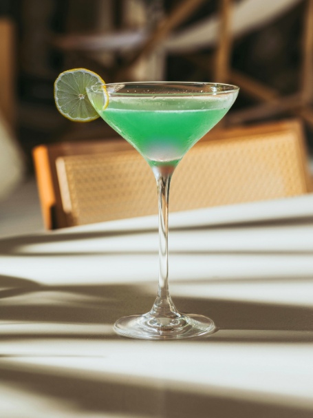 Cocktail deep valley vert servi dans un verre martini avec une rondelle de citron