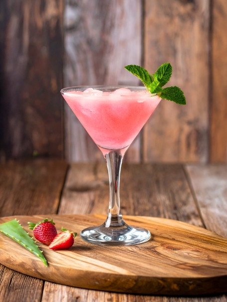 Cocktail Fresh Fruit à base de jus d'aloe vera et de fraise, dans un verre à cocktail avec de la glace et un brin de menthe fraîche.