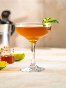 Cocktail Honey Panama dans un verre à cocktail, à base de rhum ambré des îles Old Nick, de sirop de canne Canadou, de citron vert, de miel et de feuilles Basilic frais.