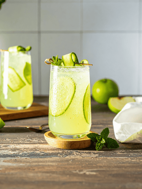 Cocktail avec de la menthe fraîche, du concombre, sirop de canne et rhum blanc servi dans un verre agrémenté de concombre frais.