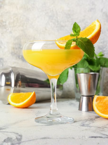 Cocktail Orange Blossom, à base de gin et de jus d'orange, servi dans un verre à cocktail.