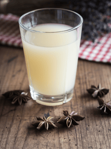 Verre de Pastis dilué avec de l'eau, créant une couleur opalescente.