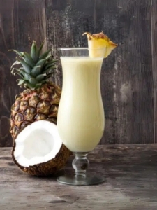 Cocktail Pina Colada avec du rhum servi dans un verre décoré avec une tranche d'ananas.