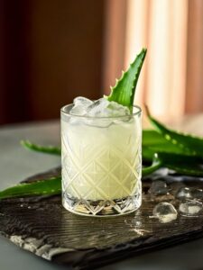 cocktail pina vera de couleur jaune clair avec des glaçons et une branche d'aloe vera