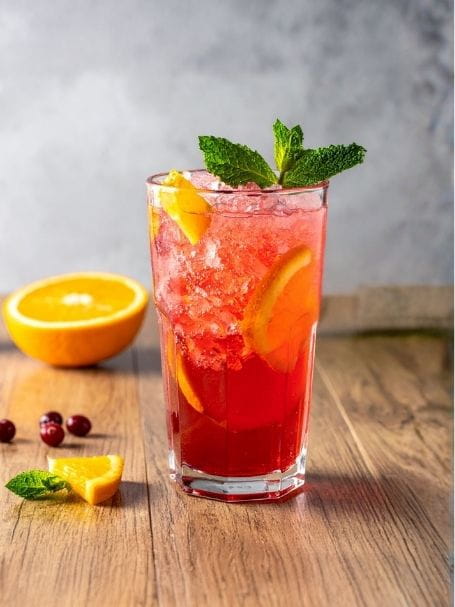 Cocktail real one avec feuilles de menthe dans un verre long drink, à base d'eau gazeuse, de cranberry et d'orange, avec des glaçons.