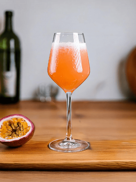 Cocktail avec du vin rosé, de la crème de pêche et du fruit de la passion servi dans un verre ballon