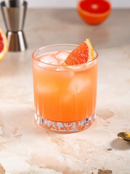 Cocktail Roussillon dans un verre à whisky, à base de Riversaltes rosé et de jus de pamplemousse, avec des glaçons.
