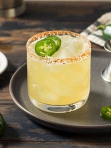 Cocktail Spicy Margarita, servi dans un verre old fashioned décoré de tranches de jalapeno et givré de poudre de piment rouge.