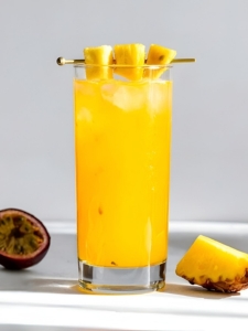 Cocktail spicy planteur avec du rhum et des épices, avec du nectar de maracuja, servi dans un verre décoré avec un tranche d'ananas