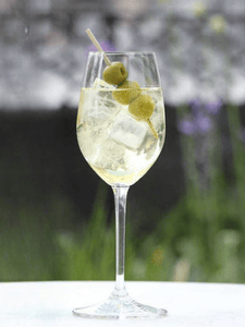 Cocktail spritz italicus, avec du prosecco et de la liqueur italicus, servi dans un verre avec des glaçons et 3 olives sur un pic