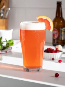 Cocktail Sweet Beer dans un verre à cocktail, à base de crème de pamplemousse, de jus de cranberry, et de bière.
