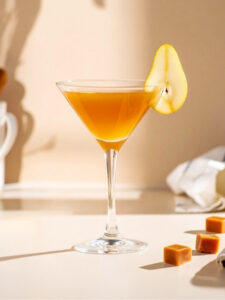 Cocktail Sweet William dans un verre à cocktail, à base de Vodka Poliakov, de nectar de poire et de sirop de caramel.