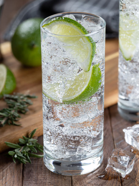 Cocktail à la Tequila, jus de citron et eau gazeuse, servi dans un verre décoré avec un zeste de citron vert.