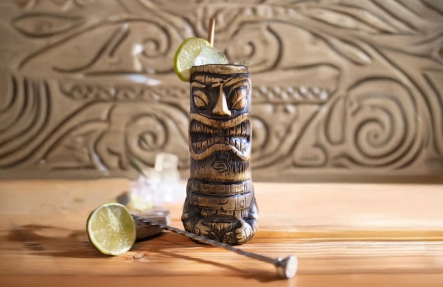 cocktail tiki dans un verre traditionnel tiki avec des glaçons e du citron vert sur une table en bois clair