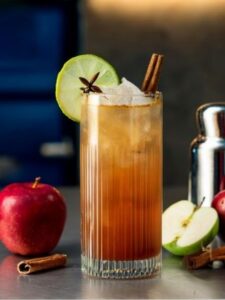 cocktail cinnamon sky servi dans un verre highball avec de la pomme et de la cannelle