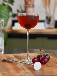 Cocktail Manhattan au Whisky et au Vermouth de couleur rouge profond dans un verre à cocktail avec une cerise confite.