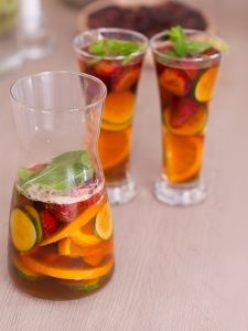 Cocktail Pimm's avec triple sec, limonade, menthe fraîche, tranches de concombre, rondelles d'orange et de citron vert, et une tranche de fraise.