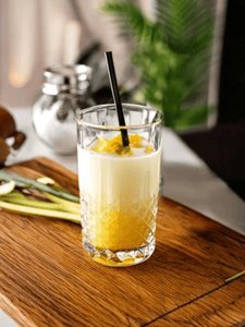 Cocktail à la vodka avec de la citronnelle, de la vanille et des fruits de la passion, servi dans un verre avec une paille.