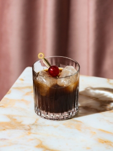 cocktail black russian à base de vodka, de liqueur de café et de cerise, servi dans un verre old fashioned.