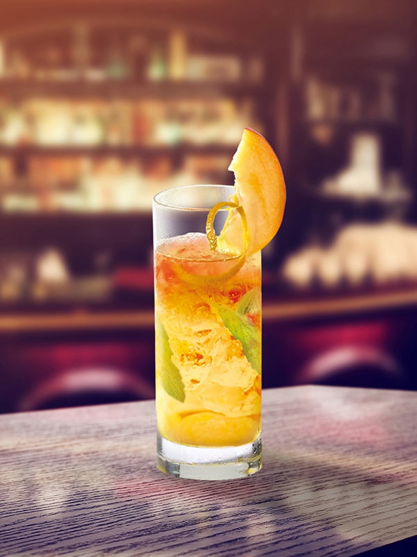 cocktail old kentucky bourbon dans un long verre avec de la pèche en décoration