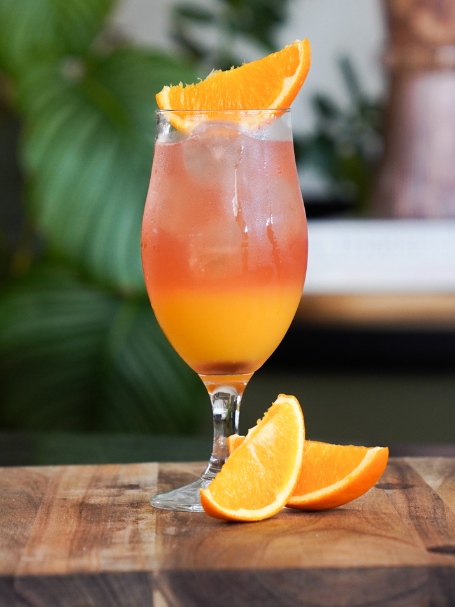 Cocktail sex on the beach avec vodka jus de cranberry servi dans un verre décoré avec un quartier d'orange.