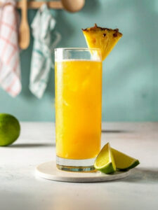 Cocktail Tropical Kamasutra dans un verre long drink, à base de Rhum VO Dillon, de Sirop de canne Canadou, de Jus d'ananas Caraïbos et d'une lamelle Gingembre, avec des glaçons et une tranche d'ananas.