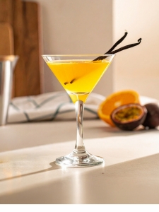 Cocktail Vanillaska dans un verre à cocktail, à base de Vodka Poliakov, de nectar de maracujà Caraïbos, de sirop de canne Canadou, de jus d'orange, d'une pincée Vanille, de jus de citron vert pressé, d'un demi fruit de la passion et de citronnelle.