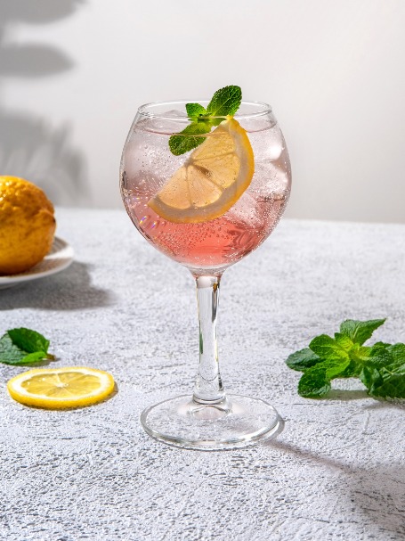 cocktail gin pink dans un verre piscine avec des fraises et des rondelles de citron vert