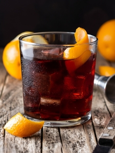 cocktail boulevardier avec du whisky et de l'amer et bitter rouge, servi dans un verre avec glaçons et zeste d'orange