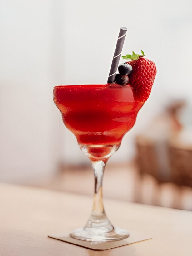 French Bowl Punch dans un verre à cocktail servi avec des fruits rouges et une paille