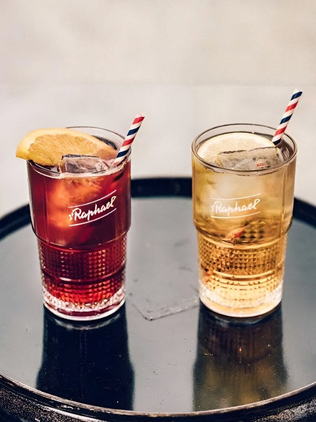 cocktail saint raph tonic servi dans un verre long drink jaune et rouge servi avec un zeste d'agrume et une paille