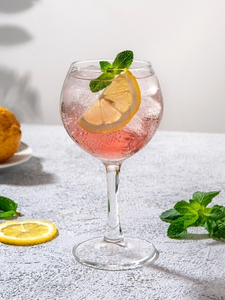 Cocktail Gin Pink Tonic dans un verre à cocktail piscine, à base de Tonic et de Gin Pink Gibson's avec des glaçons et une fraise.