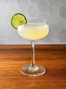Cocktail White Lady dans un verre à cocktail, à base de Gin London dry Gibson's, de Triple sec Marie Briard et de jus de citron vert pressé, avec une rondelle de citron vert sur le rebord du verre.