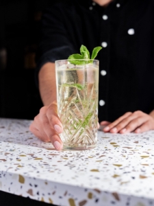 Cocktail Highball Five avec du whisky et de la limonade servi dans un verre décoré avec des feuilles de menthe