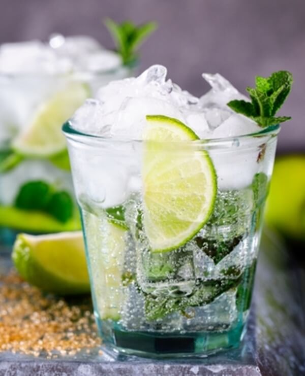 Cocktail mojito real dans un verre avec de la glace pilée, feuilles de menthe et citron vert