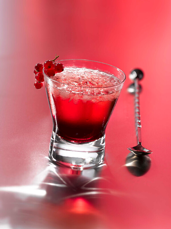 Cocktail cassis bitter dans un verre avec glace pilée et groseille