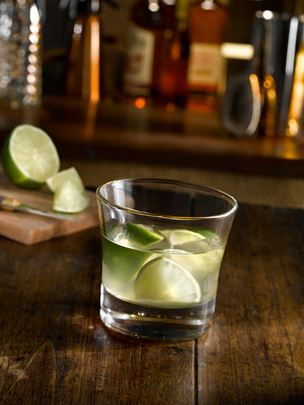 Cocktail ti punch dans un verre plat avec morceaux de citron vert