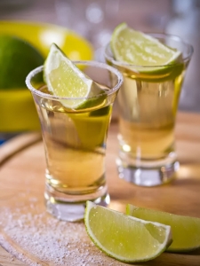 cocktail tequila paf de couleur jaune clair servi dans un shot avec un quartier de citron vert