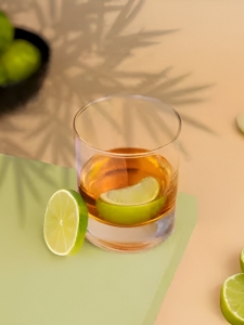 Cocktail Ti' Punch préparé avec du rhum blanc, du sirop de canne et garni d'une rondelle de citron pour une touche tropicale servi dans un verre type gobelet pour punch