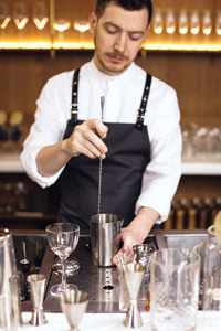 Barman qui utilise une cuillère à mélange pour préparer des cocktails