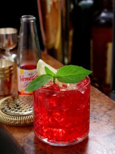 Cocktail Venezzio In Love dans un verre old fashioned posé sur un bar
