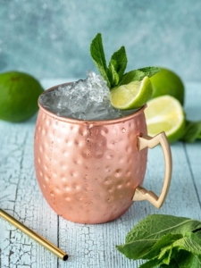 Cocktail Moscow Mule à la vodka et ginger beer, servi dans un mug en cuivre avec des glaçons, du citron vert et des feuilles de menthe
