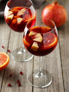 Cocktails sangria sans alcool avec du jus de raisin rouge dans un verre ballon servi avec des glaçons et tranches d'oranges.