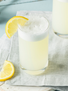 Cocktail Gin Fizz dans un verre long drink, à base de gin, de jus de citron frais et de sirop de sucre, avec une tranche de citron jaune.