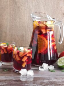 Sangria Rouge présentée dans un pichet et servie dans des verres old fashioned, garnie de morceaux de fruits.