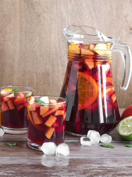 Sangria Rouge présentée dans un pichet et servie dans des verres old fashioned, garnie de morceaux de fruits.